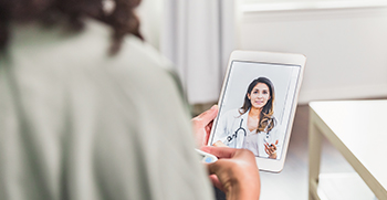 A patient attending a virtual visit with their doctor on a tablet